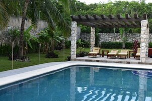 Una piscina al aire libre, sillones reclinables de piscina