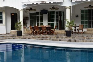 A poolside area with a dining table and chairs, a ceiling fan, and a view of the pool.
