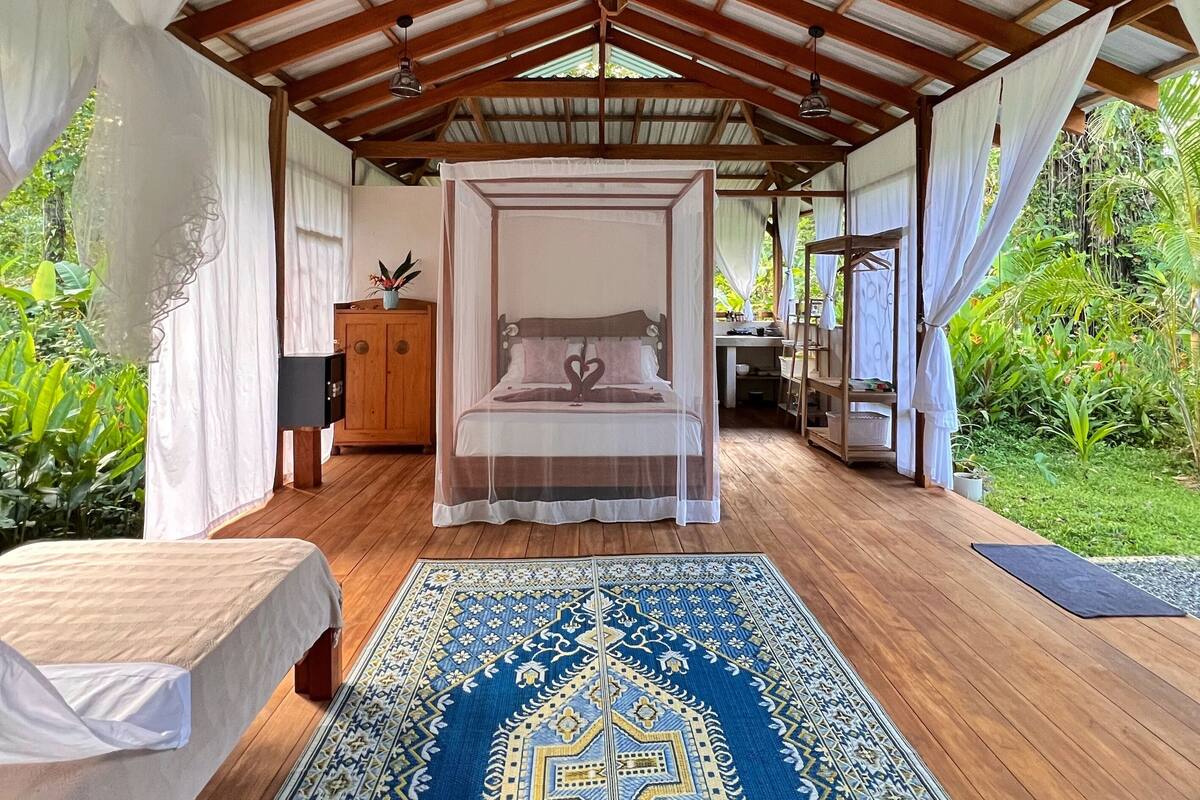 A spacious room with a large bed, a wooden floor, and a ceiling fan.