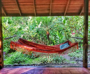 A hammock under a wooden structure surrounded by lush greenery. - Geckoes Lodge (Cahuita)