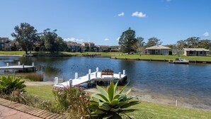 A lakeside view with a dock, a bench, and a grassy area with plants.