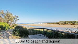 Une promenade en bois mène à une plage et à un lagon, et un panneau indique le parc national de Conjunctive.