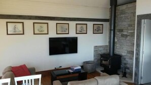 A living room with a fireplace, a television, and framed artwork on the wall.