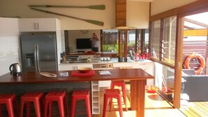 A modern kitchen with a central island, red bar stools, and a large window overlooking a deck.