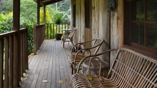 A wooden porch with a covered roof, wooden railings, and wicker furniture.