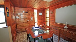 L’intérieur d’une cabane en bois, avec une table à manger, des chaises, un tableau blanc et une fenêtre.