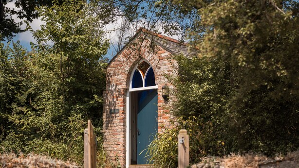 A small brick building with a blue door and a pointed arch window. - Kingfisher Barn, stunning location, private hot tub, tennis, river frontage (Saltash)