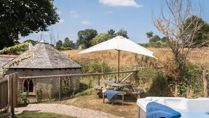 A rustic outdoor setting with a hot tub, wooden picnic table, and umbrella. - Kingfisher Barn, stunning location, private hot tub, tennis, river frontage (Saltash)