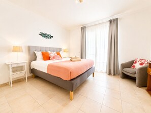 Une chambre à coucher avec un lit, des tables de chevet, une chaise et une fenêtre avec des rideaux.