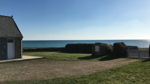 Une propriété située sur la côte, avec un bâtiment en pierre, un chemin de gravier et une vue sur la mer.