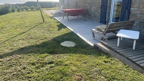 Une maison en pierre avec un patio, une balançoire et une vue sur la mer.