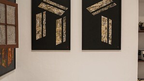 Ein Wohnzimmer mit einem beigefarbenen Sofa, einem Glastisch und zwei gerahmten abstrakten Bildern an der Wand.