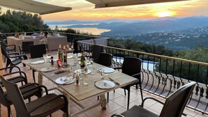 A terrace with a table set for dining, overlooking a scenic landscape with mountains and a body of water. - Large Family Villa, Les Issambres private pool, gorgeous sea views, 5 bedrooms (Roquebrune-sur-Argens)