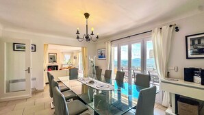 A dining area with a glass table and chairs, a chandelier, and a view of the outdoors. - Large Family Villa, Les Issambres private pool, gorgeous sea views, 5 bedrooms (Roquebrune-sur-Argens)