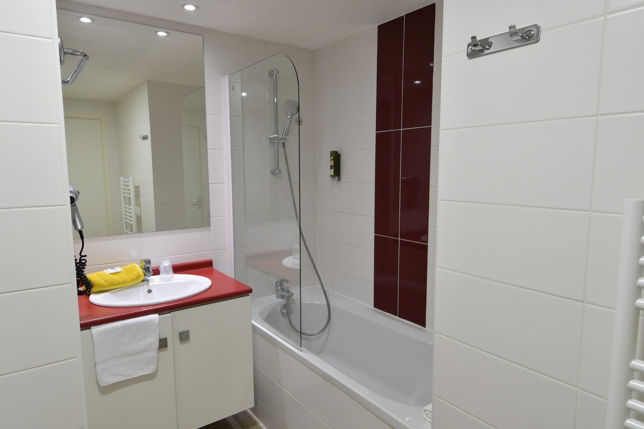 Ein Badezimmer mit einem weißen Waschbecken, einer roten Arbeitsplatte und einer Duschkabine.