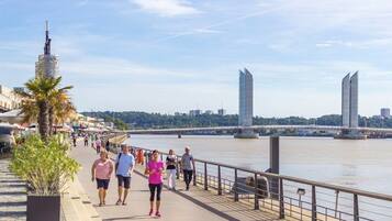 A pedestrian walkway along a river with a bridge in the background.