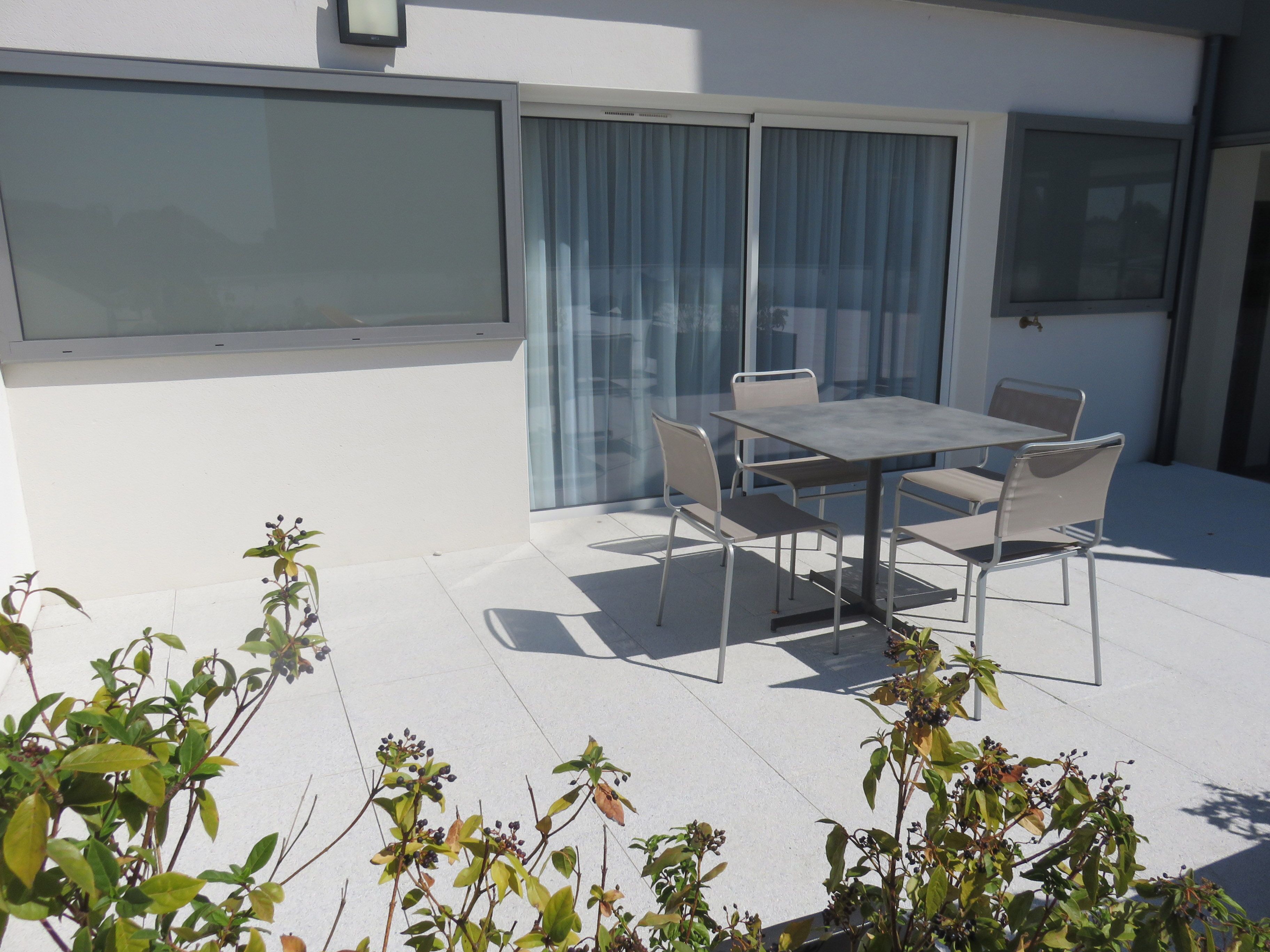Una veranda con tavolo e sedie, una porta scorrevole in vetro e vista sulla campagna circostante.