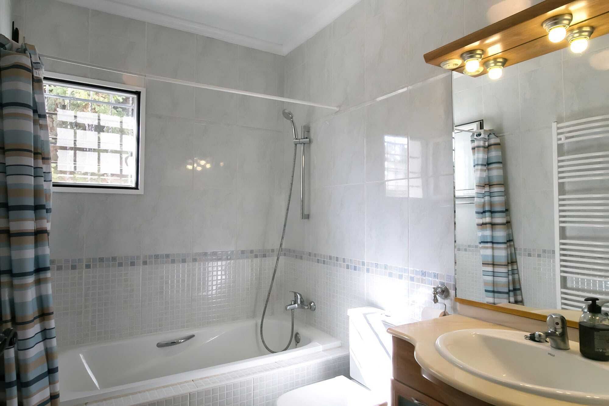 Un baño moderno con bañera, ducha, inodoro y lavabo.