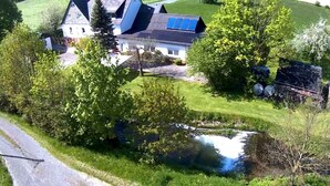 Uma casa com telhado inclinado, painéis solares e um lago.
