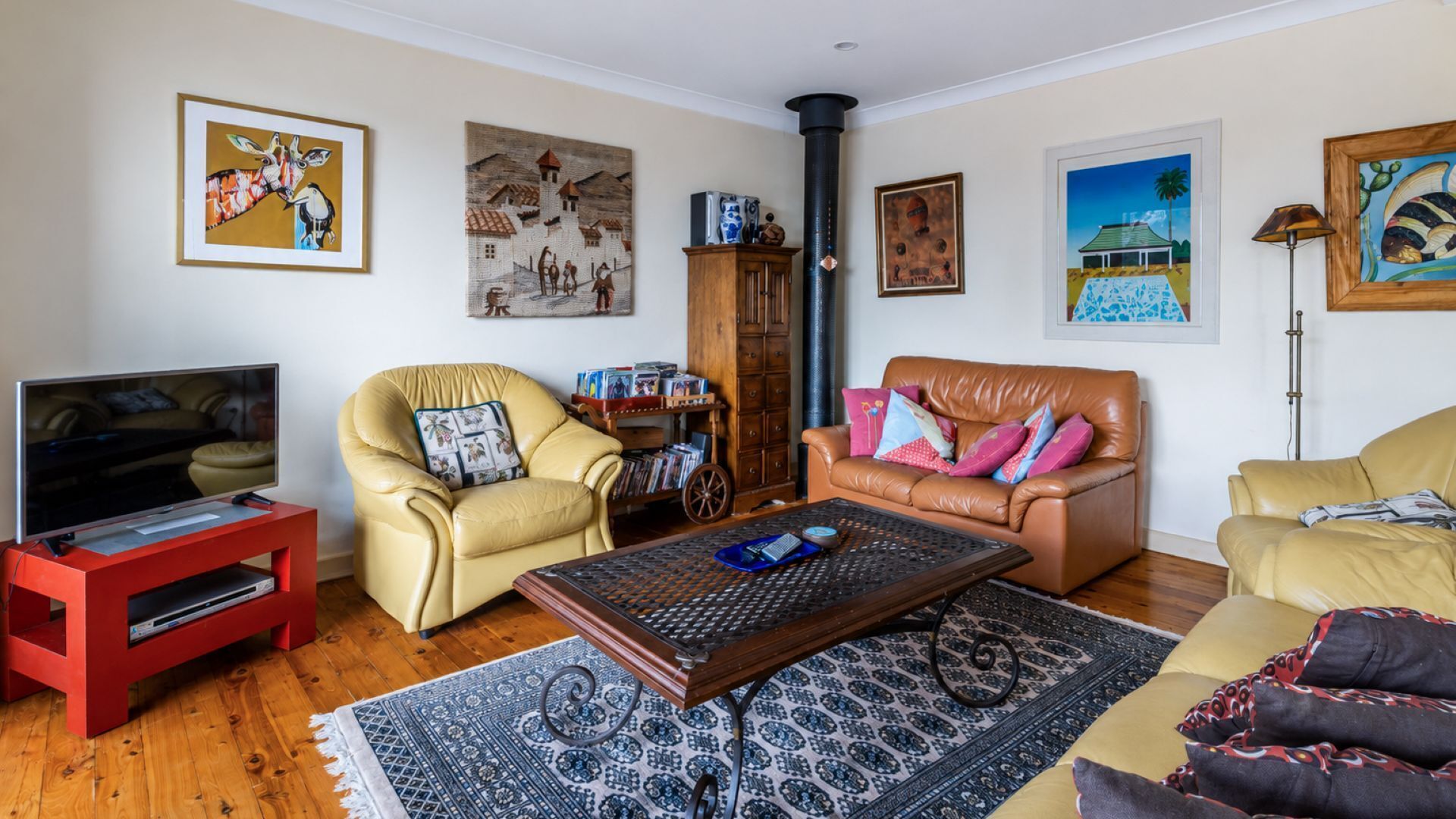 A living room with a television, leather armchairs, a coffee table, and artwork on the walls.