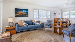 Una sala de estar con un sofá azul, un tapete redondo y un comedor con muebles de madera.