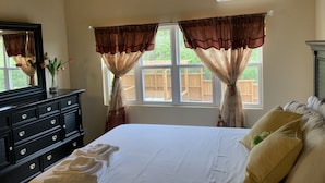 A bedroom with a bed, a dresser, and a window with curtains. - Tranquil Falmouth Harbour View Villa (Piccadilly)