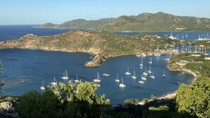 A coastal view with boats anchored in a bay, surrounded by hills and sparse vegetation. - Tranquil Falmouth Harbour View Villa (Piccadilly)