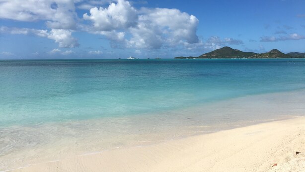 A beach with clear turquoise water, a sandy shore, and distant islands. - Tranquil Falmouth Harbour View Villa (Piccadilly)