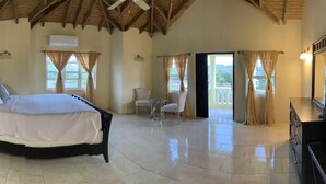 A bedroom with a bed, a desk, a chair, a table, and a balcony with curtains. - Tranquil Falmouth Harbour View Villa (Piccadilly)