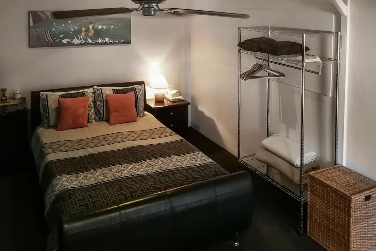 Un dormitorio con cama, ducha suspendida, ventilador de techo y mesita de noche con lámpara.
