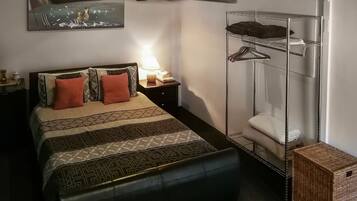 Un dormitorio con cama, ducha suspendida, ventilador de techo y mesita de noche con lámpara.