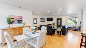 A modern living room with a glass dining table, a sofa, and a TV mounted on the wall. - Point Loma 3 bedroom/2bath (San Diego)