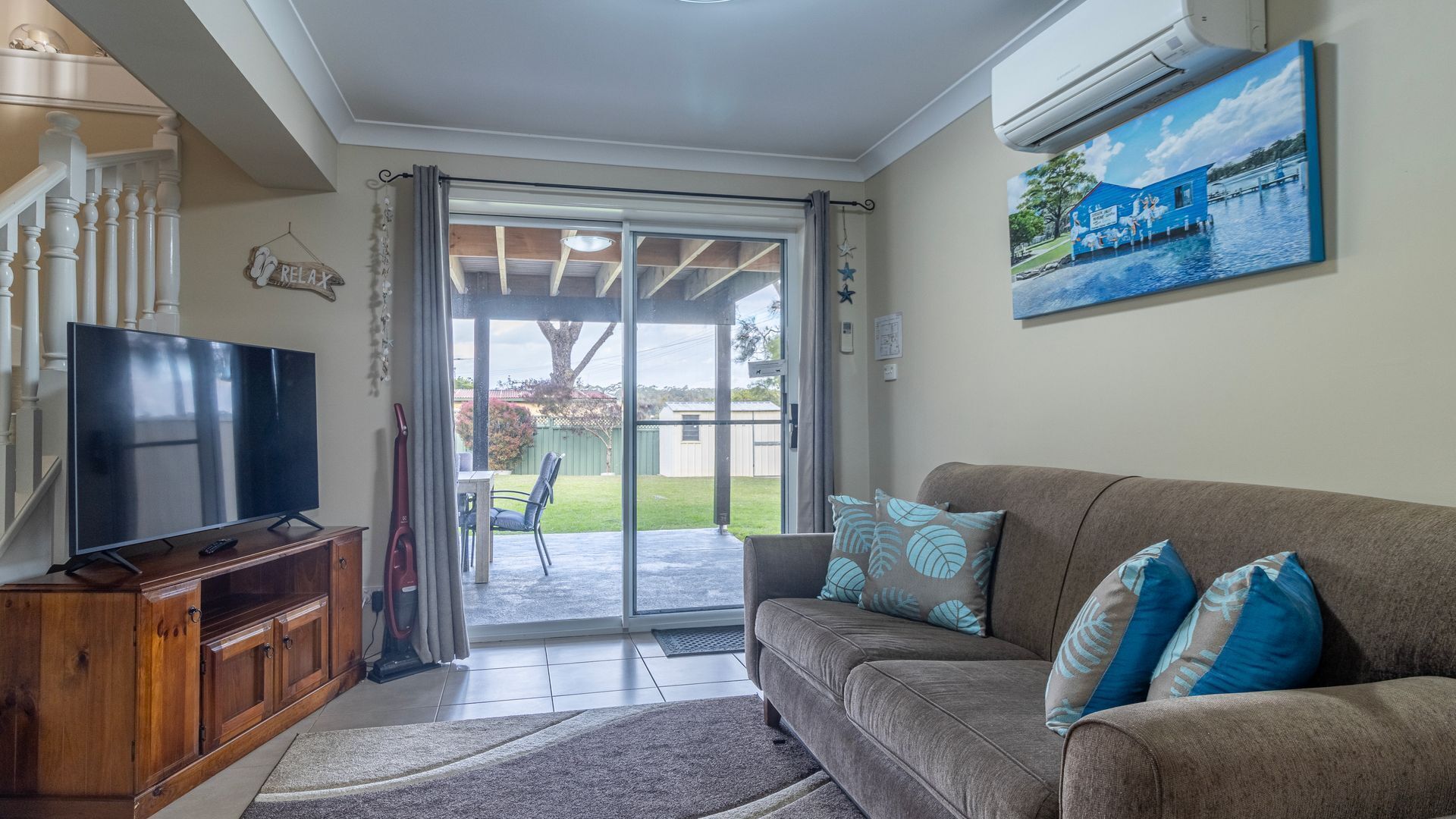 A living room with a TV, wooden cabinet, and a couch with patterned cushions.