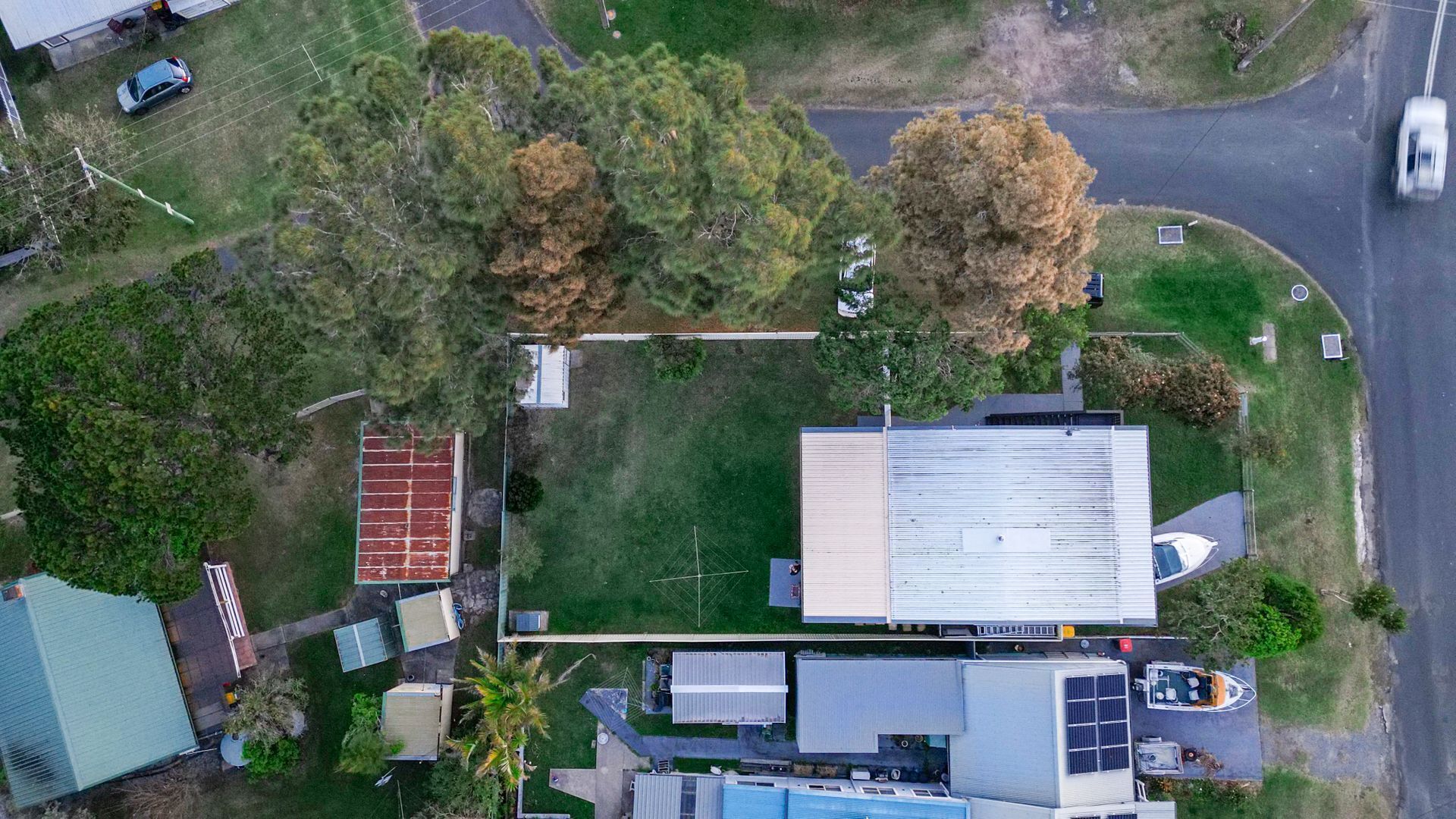 An aerial view of a property with a large building, a tennis court, and a parking area.