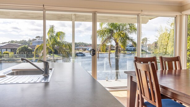 A modern kitchen with a large window overlooking a marina and palm trees. - Unbeatable Waterfront Location (Sussex Inlet)
