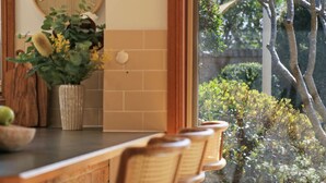 Una encimera de cocina con una planta en maceta, un cuenco blanco y una silla de madera.