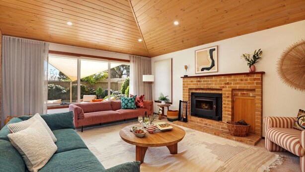 Una sala de estar acogedora con chimenea, un sofá, una mesa de centro y vistas al exterior.
