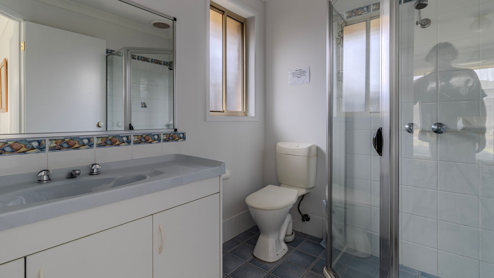 Et badeværelse med bruser, toilet og håndvask med spejl.
