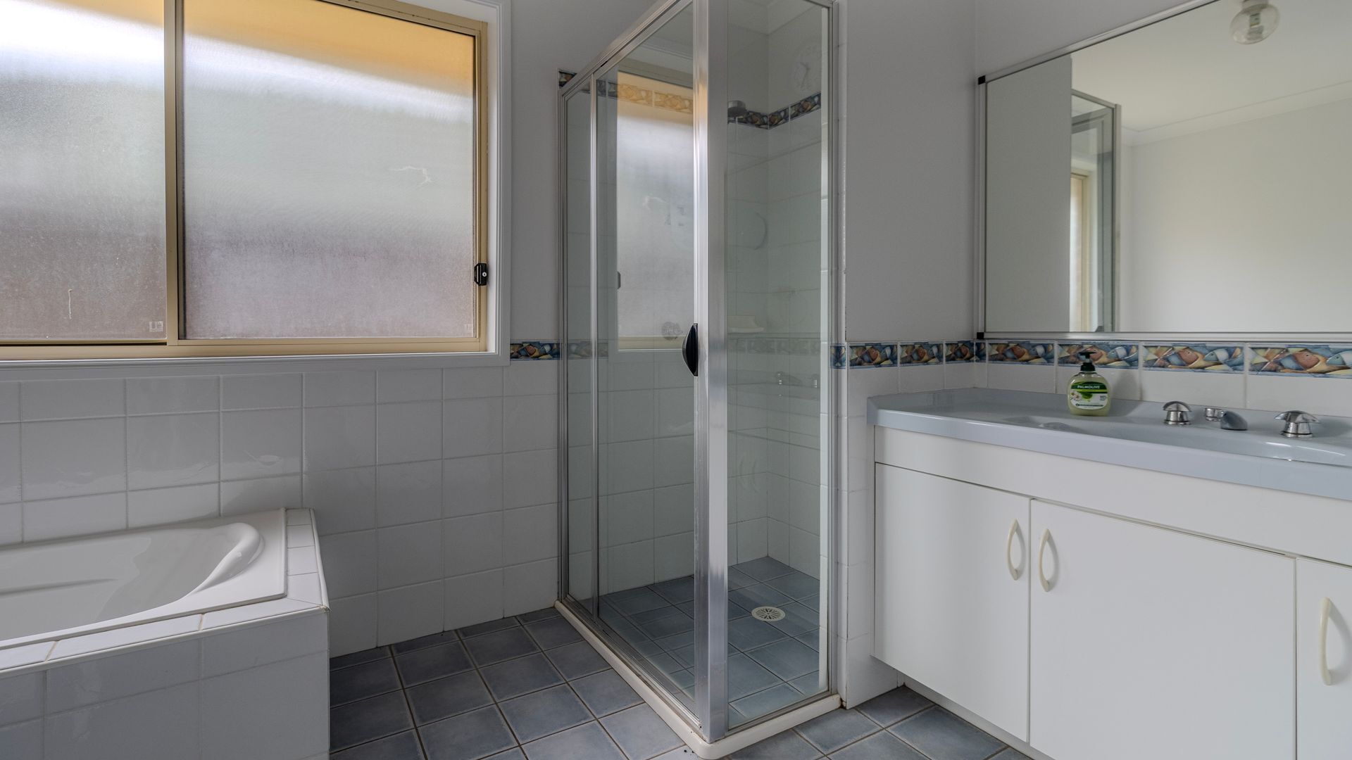 A bathroom with a shower, a sink, and a mirror.