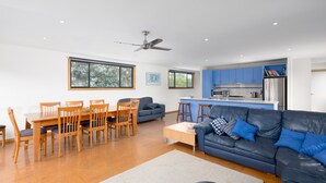 A modern living room with a dark blue leather sofa, wooden dining table, and chairs.