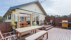 A modern house with a deck, a dining area, and a barbecue grill.
