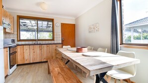 A compact kitchen with wooden cabinets, a large window, and a dining table with chairs. - Perfect family holiday (Berrara)