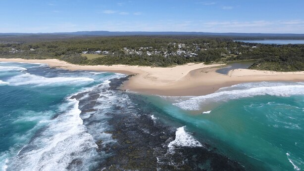 An aerial view of a coastal area with a beach, rocky shoreline, and a forested background. - Perfect family holiday (Berrara)