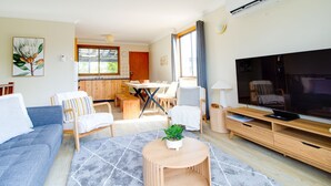 A living room with a sofa, chairs, a coffee table, a TV, and a dining area with a table and chairs. - Perfect family holiday (Berrara)