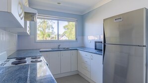 Eine moderne Küche mit weißen Schränken, einem Edelstahl-Kühlschrank, einer Mikrowelle und einem Gasherd.