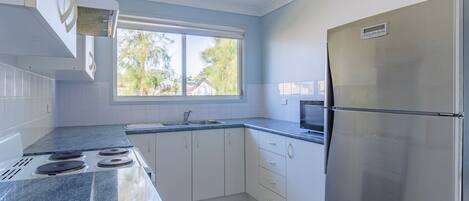 Une cuisine moderne avec des meubles blancs, un réfrigérateur en acier inoxydable, un four à micro-ondes et une cuisinière à gaz.