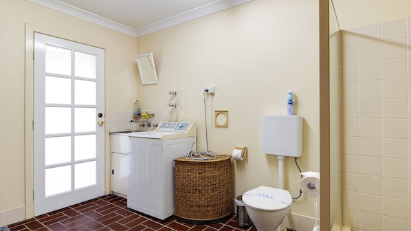 Un cuarto de lavado con lavadora, secadora, cesta de mimbre, inodoro y calentador de agua.