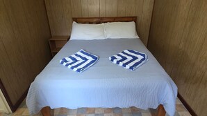 Un llit amb un llençol blanc i dues tovalloles ratllades.