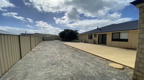 A building with a concrete patio, a fenced area, and a tree in the background.