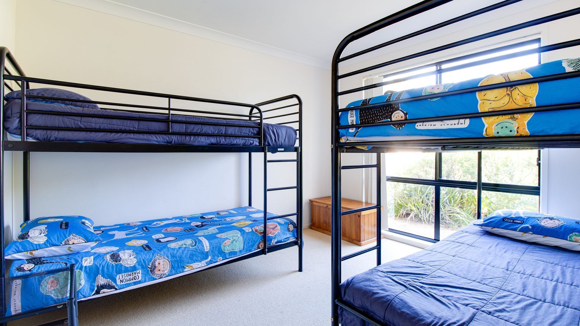 A dormitory room with two bunk beds, each with a blue mattress and matching bedding.